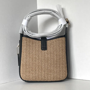 Handbag with woven design and black trim on a white background