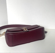 Load image into Gallery viewer, A dark burgundy pebbled leather shoulder bag with a gold-tone turn-lock clasp and a matching leather strap, resting on a white surface against a white background.