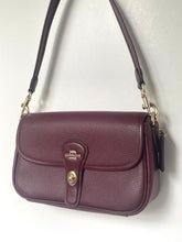 Load image into Gallery viewer, A Coach pebbled leather shoulder bag in a deep burgundy color, featuring a front flap with a gold-tone logo plate and a matching burgundy leather strap.