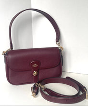 Load image into Gallery viewer, A burgundy pebbled leather shoulder bag with a gold-tone logo on the front flap, shown with its matching detachable shoulder strap on a white background.