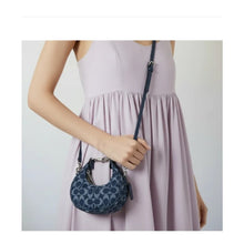 Load image into Gallery viewer, Woman holding a blue handbag with a plain background