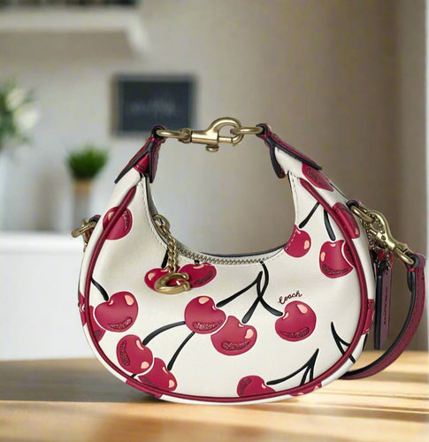 Coach handbag with cherry design on a white background