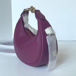 Purple handbag with a glittery strap on a white surface