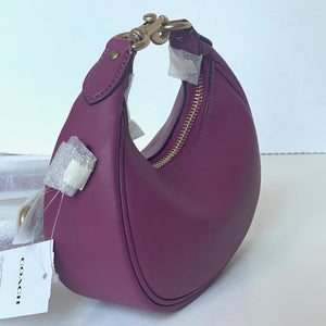 Purple handbag with gold zipper and tag on a white background