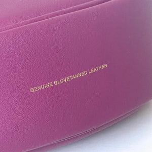 Close-up of a pink leather product with 'Genuine Glovetanned Leather' text.
