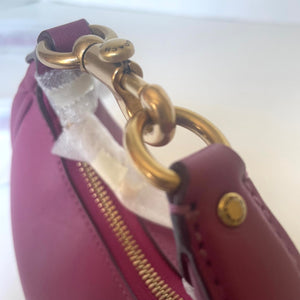 Close-up of a pink handbag with gold hardware on a white background