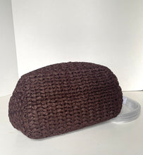 Load image into Gallery viewer, A dark brown crocheted or knitted soft bag with a rounded rectangular shape, shown on a plain white studio background with a small clear plastic prop beside it.