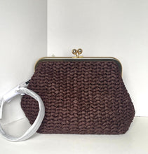 Load image into Gallery viewer, A dark brown chunky knit clutch purse with a gold-tone kiss-lock clasp and a white fabric wristlet strap, set against a plain white background.