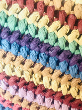 Load image into Gallery viewer, A close-up of a woven textile or rug featuring horizontal bands of purple, blue, beige, green, and reddish-brown textured fibers.