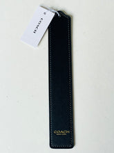 Load image into Gallery viewer, A Coach black leather bookmark with gold foil branding and a white paper tag, shown on a light off-white background.