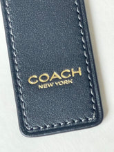 Load image into Gallery viewer, Close-up of a Coach New York leather keychain tag in navy blue with gold lettering and white stitching, shown on a light off-white background.