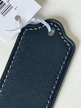 Load image into Gallery viewer, A close-up of a dark navy blue leather luggage tag with white contrast stitching and a white hangtag attached, set against a light off-white background.