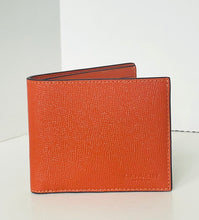 Load image into Gallery viewer, An orange textured leather bifold wallet standing upright on a white surface against a white background.