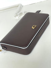 Load image into Gallery viewer, A dark brown pebbled leather pouch or wallet with a small gold-tone crescent moon logo, shown on a light gray surface.