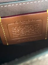 Load image into Gallery viewer, Close-up of a Coach interior label patch on a dark brown leather item, showing embossed branding and stitching details.