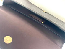 Load image into Gallery viewer, Close-up of a dark brown textured leather handbag interior, showing a gold-tone circular metal emblem and a dark brown lining.