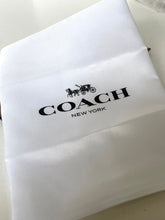 Load image into Gallery viewer, A close-up of a white Coach New York dust bag or fabric pouch with the black Coach logo and carriage emblem printed on the front.