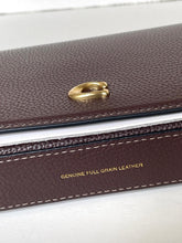 Load image into Gallery viewer, Close-up of a dark brown textured leather item, likely a wallet or case, with a gold-tone ring clasp and gold lettering that reads 'GENUINE FULL GRAIN LEATHER' on the front.