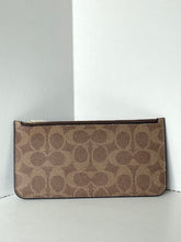 Load image into Gallery viewer, A Coach canvas clutch pouch in the signature brown and tan monogram pattern, featuring a dark brown leather zipper trim and a small gold-tone metal pull tab, set against a minimalist white corner background.
