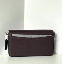 Load image into Gallery viewer, A dark brown pebbled leather crossbody bag with a gray fabric accent strip across the front pocket, resting on a white surface against a white background.