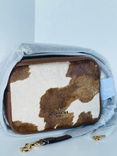 Load image into Gallery viewer, Coach handbag with cow print pattern on a light gray background