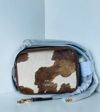 Load image into Gallery viewer, Coach bag with cow print design on a light gray background