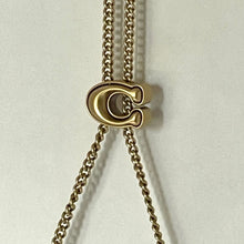 Load image into Gallery viewer, Gold necklace with a unique pendant on a light gray background