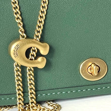 Load image into Gallery viewer, Gold chain with a gold 'C' pendant on a green leather bag.