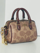 Load image into Gallery viewer, Coach handbag with gold keychain on a white background