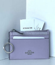 Load image into Gallery viewer, A Coach card holder wallet in a light lavender purple leather with a silver-tone key ring and zipper, shown with branded cards tucked inside against a white background.