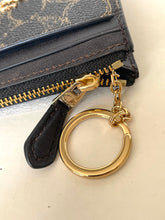 Load image into Gallery viewer, Gold keychain attached to a black wallet on a light beige background