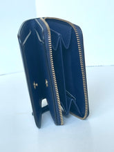 Load image into Gallery viewer, A navy blue leather zip-around wallet standing open to show its interior card slots and compartments, featuring gold-tone metal hardware and zipper trim, set against a plain white background.