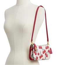 Load image into Gallery viewer, Woman wearing a white shirt and black pants with a red and white patterned handbag.
