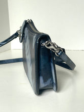 Load image into Gallery viewer, A dark navy blue leather crossbody bag with a glossy finish, featuring silver-tone hardware and a matching navy strap, shown from a side profile view on a white surface.