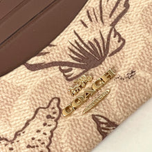 Load image into Gallery viewer, Close-up of a Coach wallet with gold hardware on a patterned background