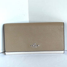 Load image into Gallery viewer, Beige wallet with Coach logo on a light wooden surface