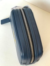 Load image into Gallery viewer, A navy blue pebbled leather zippered pouch with silver-tone metal zippers and white contrast stitching, shown on a light beige surface.