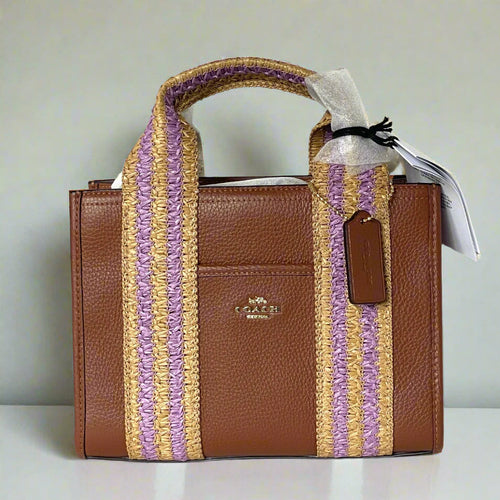 Brown handbag with woven purple and beige handle on a white background
