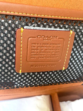 Load image into Gallery viewer, Close-up of a Coach wallet with a brand label on a textured background