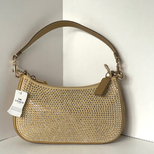 Beige handbag with rhinestone embellishments on a light background