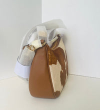 Load image into Gallery viewer, A small shoulder bag with a brown and cream cowhide pattern and smooth brown leather trim, shown standing upright against a plain white background.