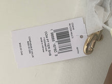 Load image into Gallery viewer, A white paper retail price tag attached to a white garment with a gold metal clasp, photographed on a light off-white fabric background.