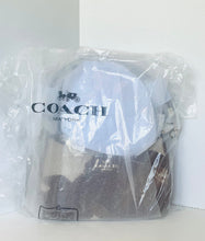 Load image into Gallery viewer, A Coach New York handbag inside a clear plastic protective bag, with the Coach logo printed on the front. The bag features a white top section and a dark brown textured lower section.