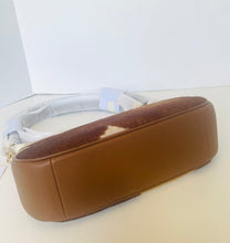 Load image into Gallery viewer, A brown leather shoulder bag with a mixed brown and white cowhide patch on the top flap, resting on a light beige surface against a white background.