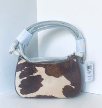 Load image into Gallery viewer, A small shoulder bag with a brown and cream cowhide pattern, featuring a clear plastic-wrapped handle and a white product tag attached, set against a white background.