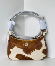 Load image into Gallery viewer, A Coach shoulder bag in brown and cream cowhide with a light gray strap, shown in a clean white studio corner.