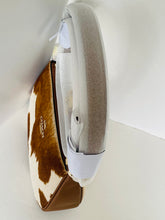 Load image into Gallery viewer, A Coach shoulder bag with a brown and white cowhide pattern and brown leather trim, shown standing upright against a white background.