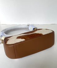 Load image into Gallery viewer, A brown leather shoulder bag with a brown and cream cowhide-patterned top flap, shown on a plain white background with its white strap still partially wrapped in protective plastic.