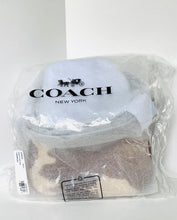 Load image into Gallery viewer, A Coach New York handbag inside its clear plastic packaging, with the black Coach logo and carriage graphic printed on the front.