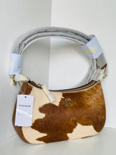 Load image into Gallery viewer, A Coach shoulder bag in brown and cream cowhide with a gray fabric-wrapped handle, gold-tone hardware, and a white hangtag on a white background.